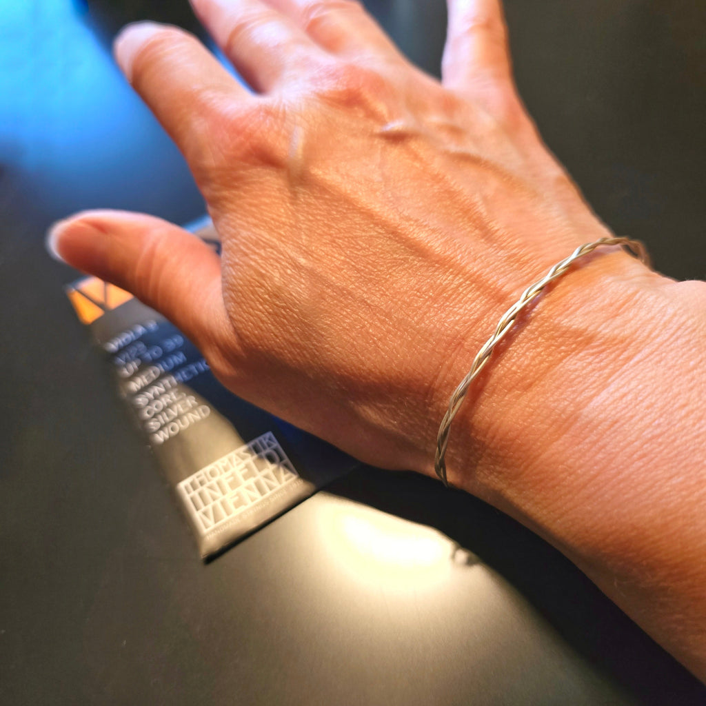 Hand with an Upcycled Viola String Bracelet (viola string package in background)