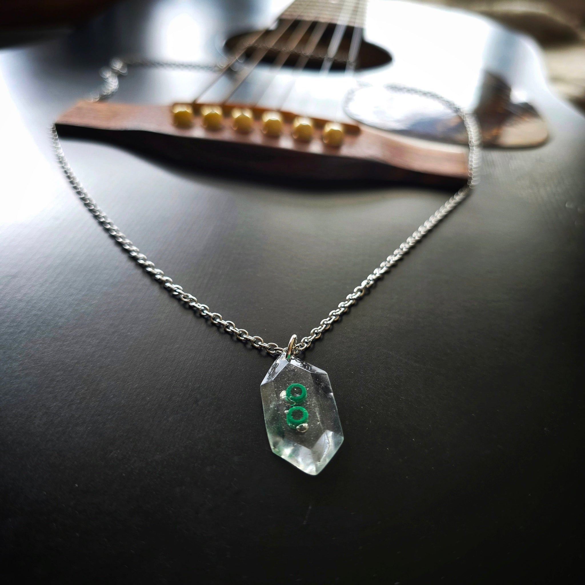 Hexagone Resine Pendant with Green Guitar String Ballends Necklace on Black Guitar