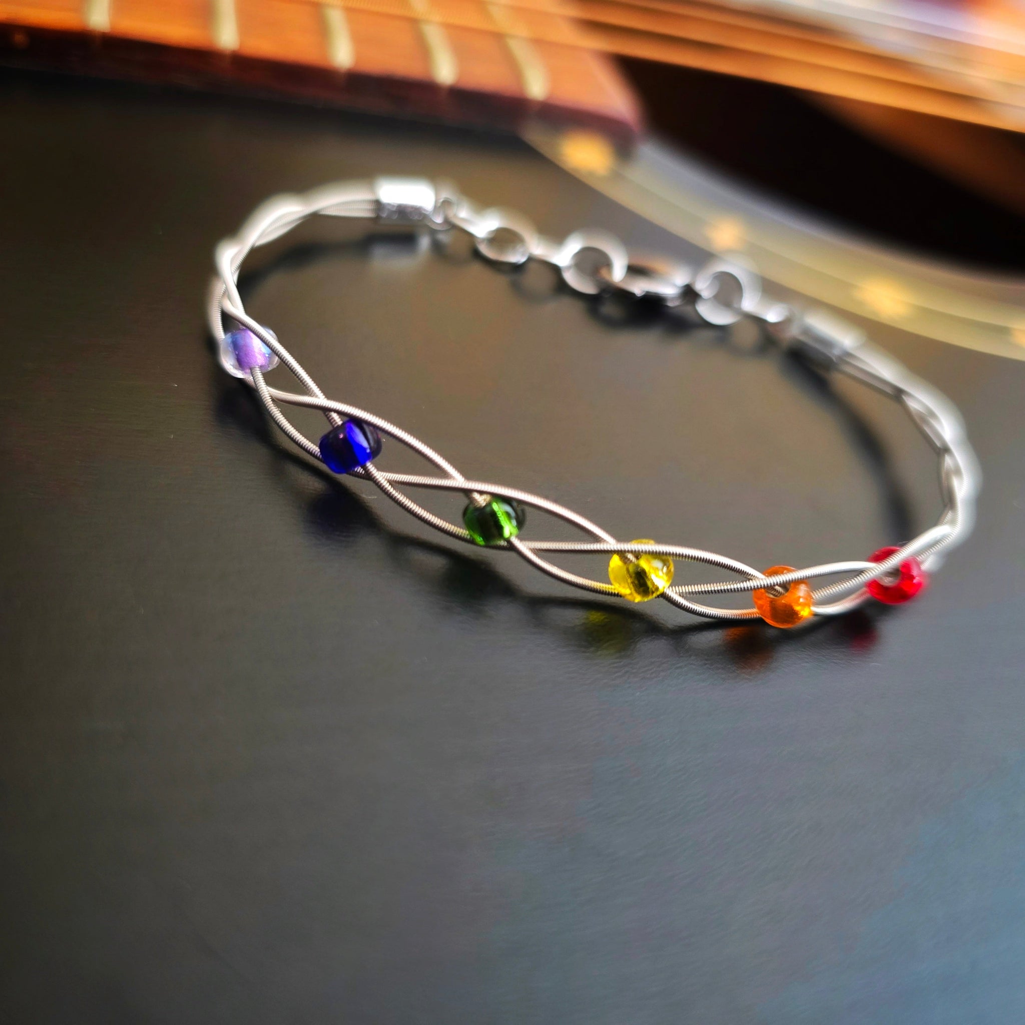 LGBT Pride Bracelet with Braided Guitar Strings on Black Guitar Close-up
