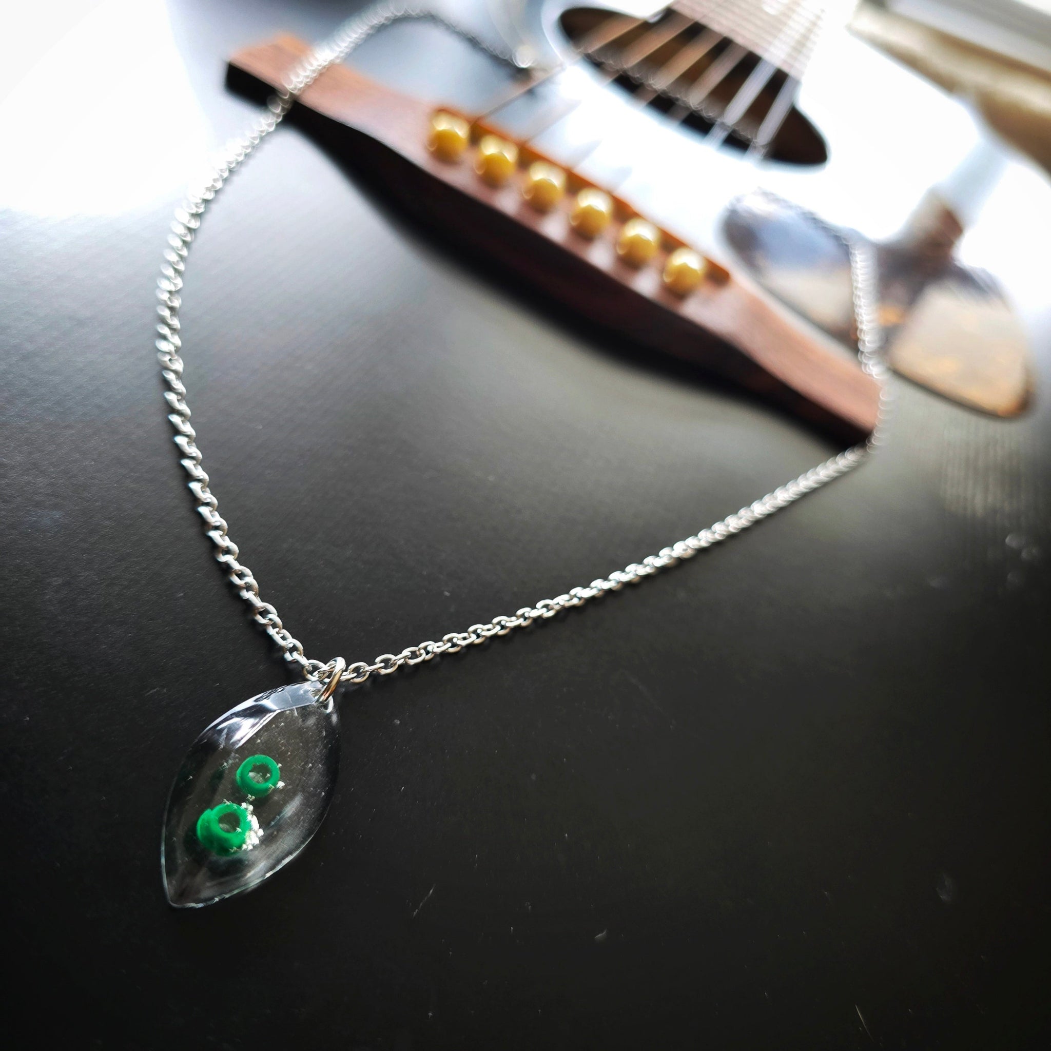 Marquise Shaped Resin Pendant with Green Guitar String Ballends on Black Guitar