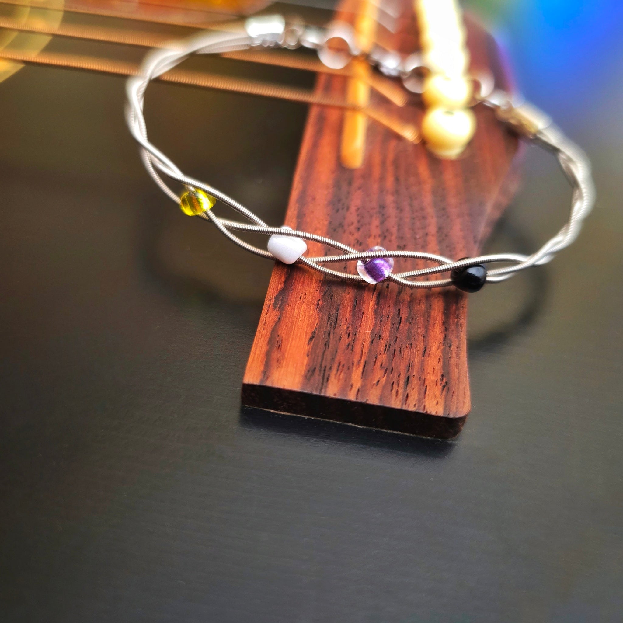 Non-Binary Pride Three Guitar String Braided Clasp Bracelet on Guitar Bridge