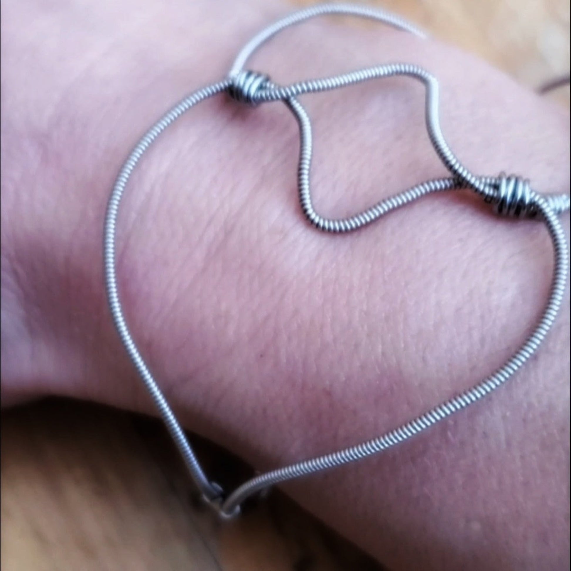guitar string bracelet in the shape of a heart, on a wrist