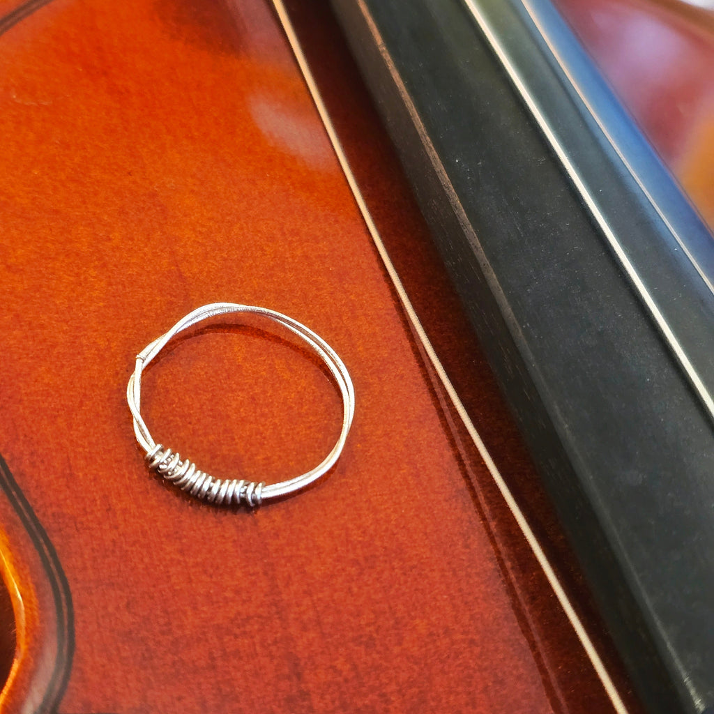 Silver  coloured violin string ring on a violin surface