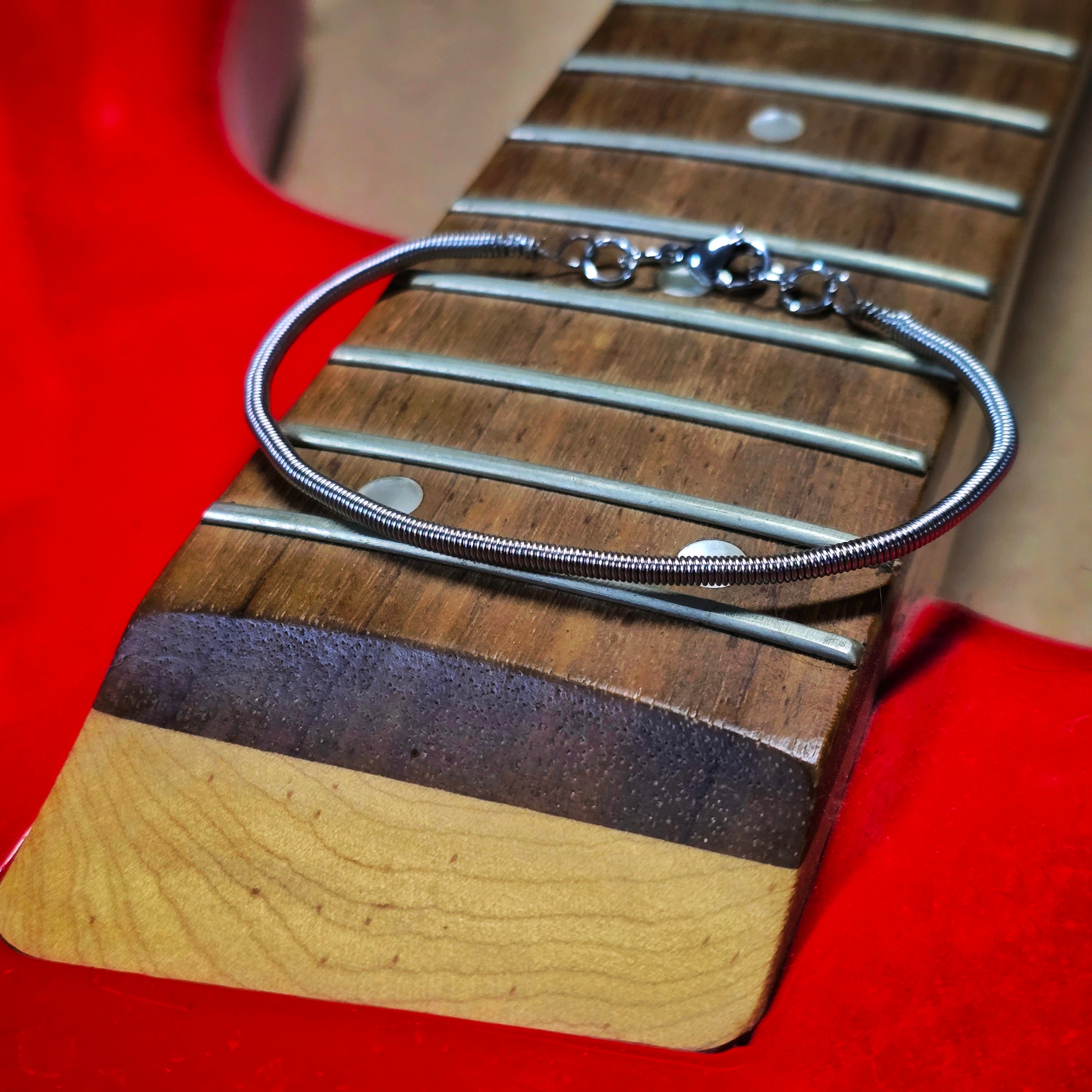 Simple Bass String Bracelet on Red Bass Guitar Neck