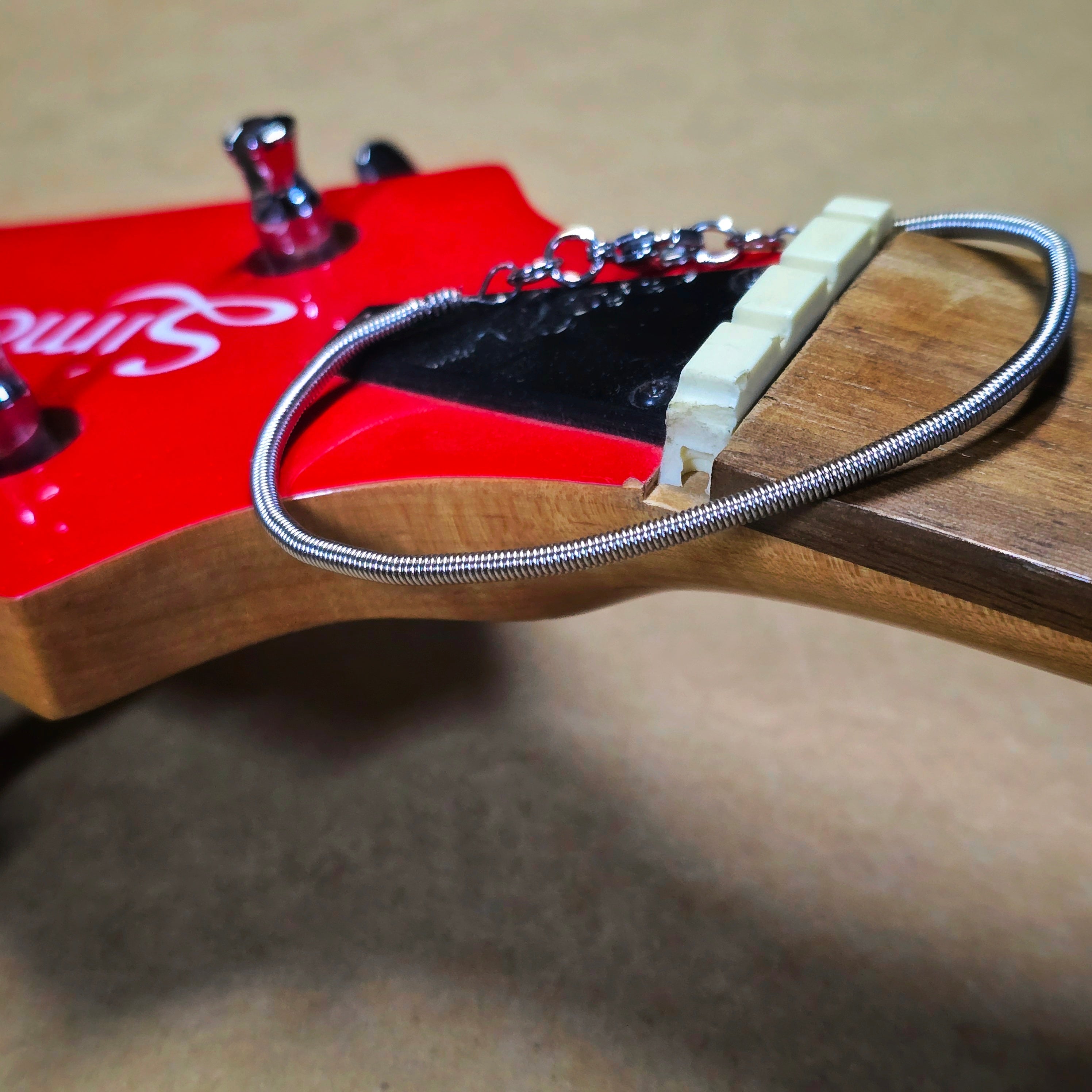 Simple Bass String Bracelet on Top of Neck of Red Bass Guitar Neck