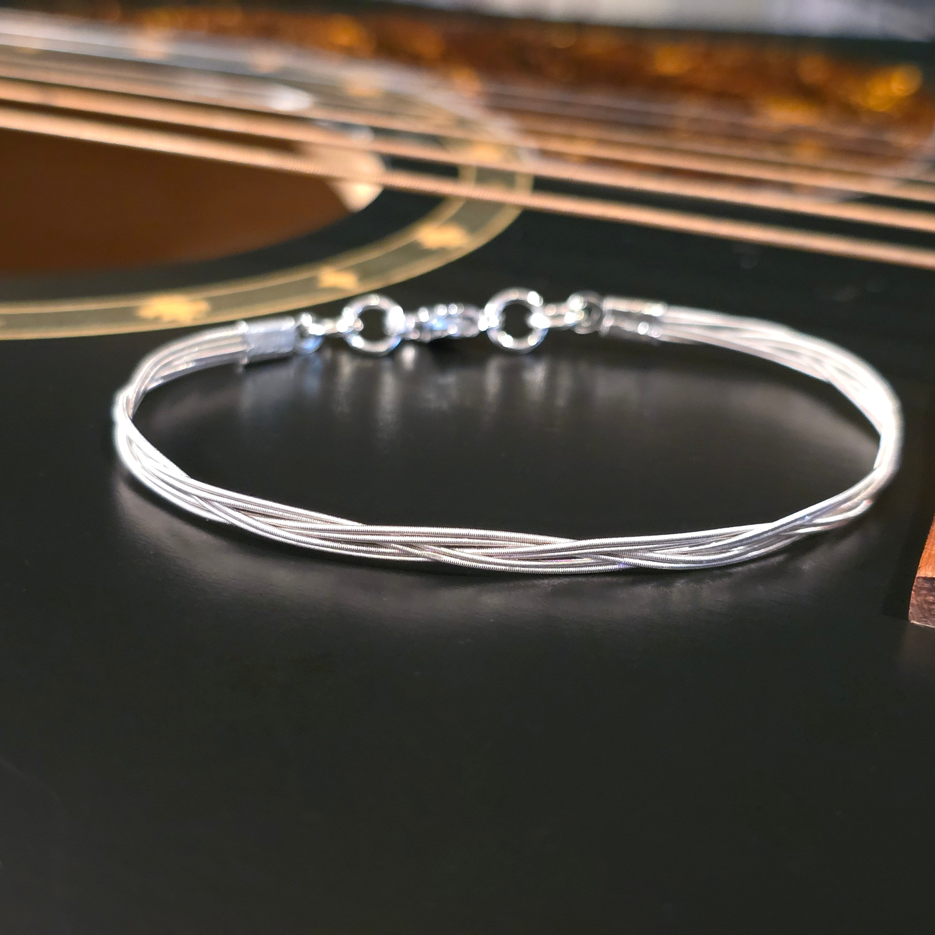 Six string guitar stringbracelet on black guitar 
