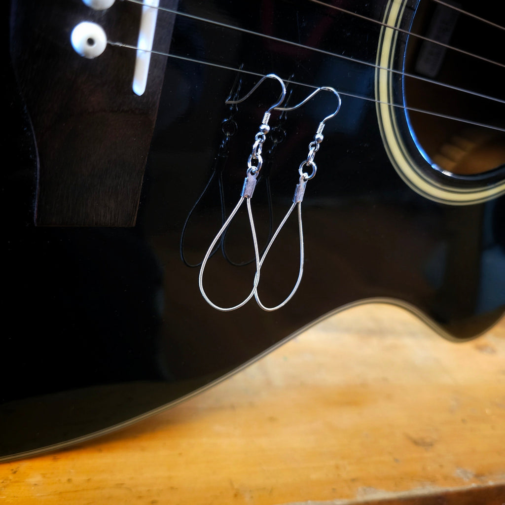 Teardrop Guitar String Earrings on Black Background and Blue Measuring Tape