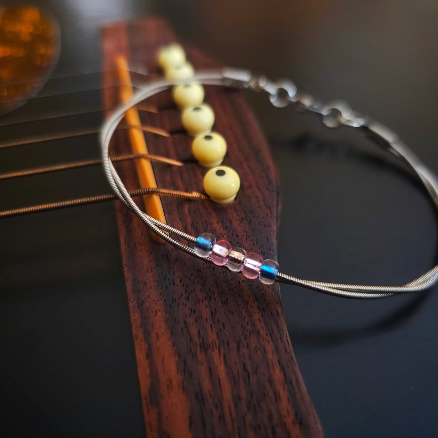 Trans pride guitar string bracelet on black guitar 