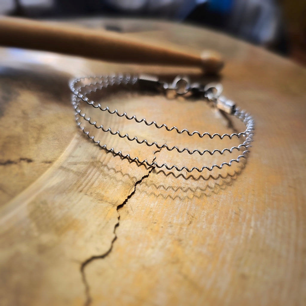 Upcycled 3 String Snare Drum Bracelet on Cymbal Drumstick in Background