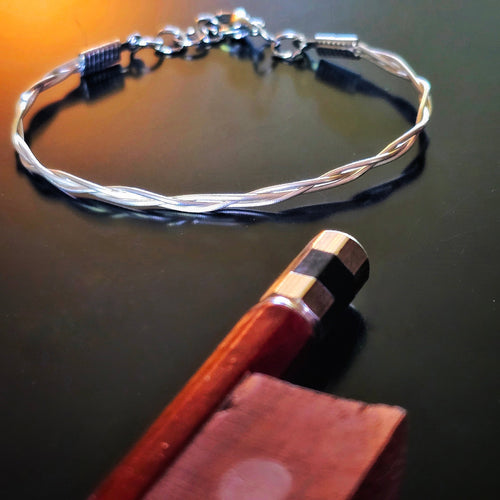 Upcycled Braided Viola String Bracelet on dark background near the end of a bow