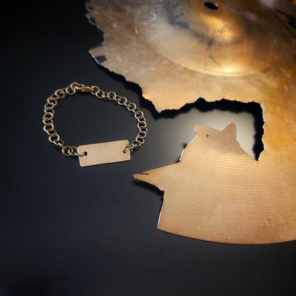 Upcycled Cymbal Piece Chain Style Bracelet next to a broken Cymbal