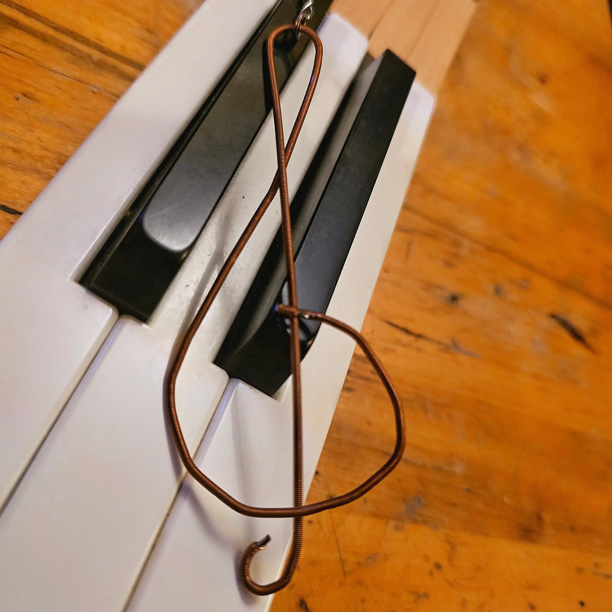Upcycled Piano String Treble Clef Ornament on Piano Keys