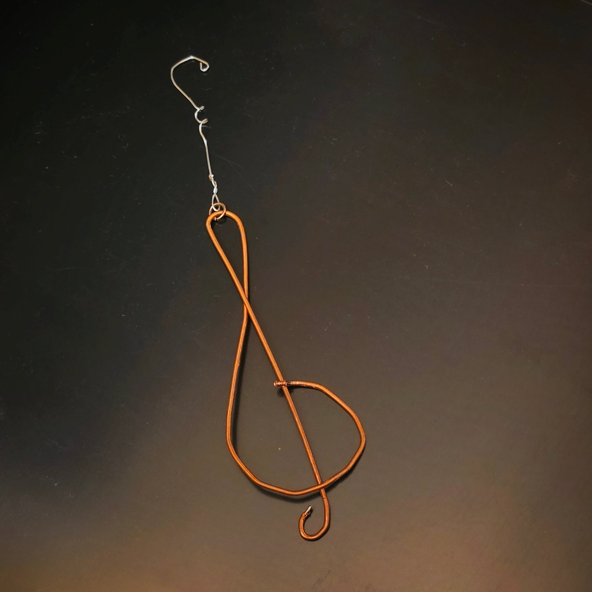 Upcycled Piano String Treble Clef Ornament on Dark Background