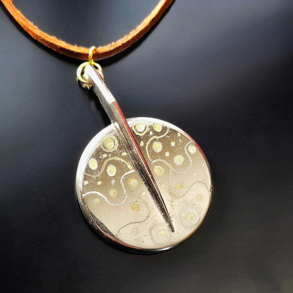 Upcycled saxophone key pendant on a black background