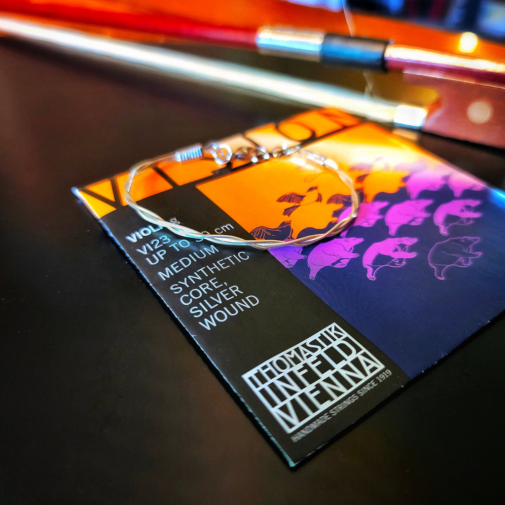 Violin bow string with an upcycled viola string bracelet on a viola string packaging
