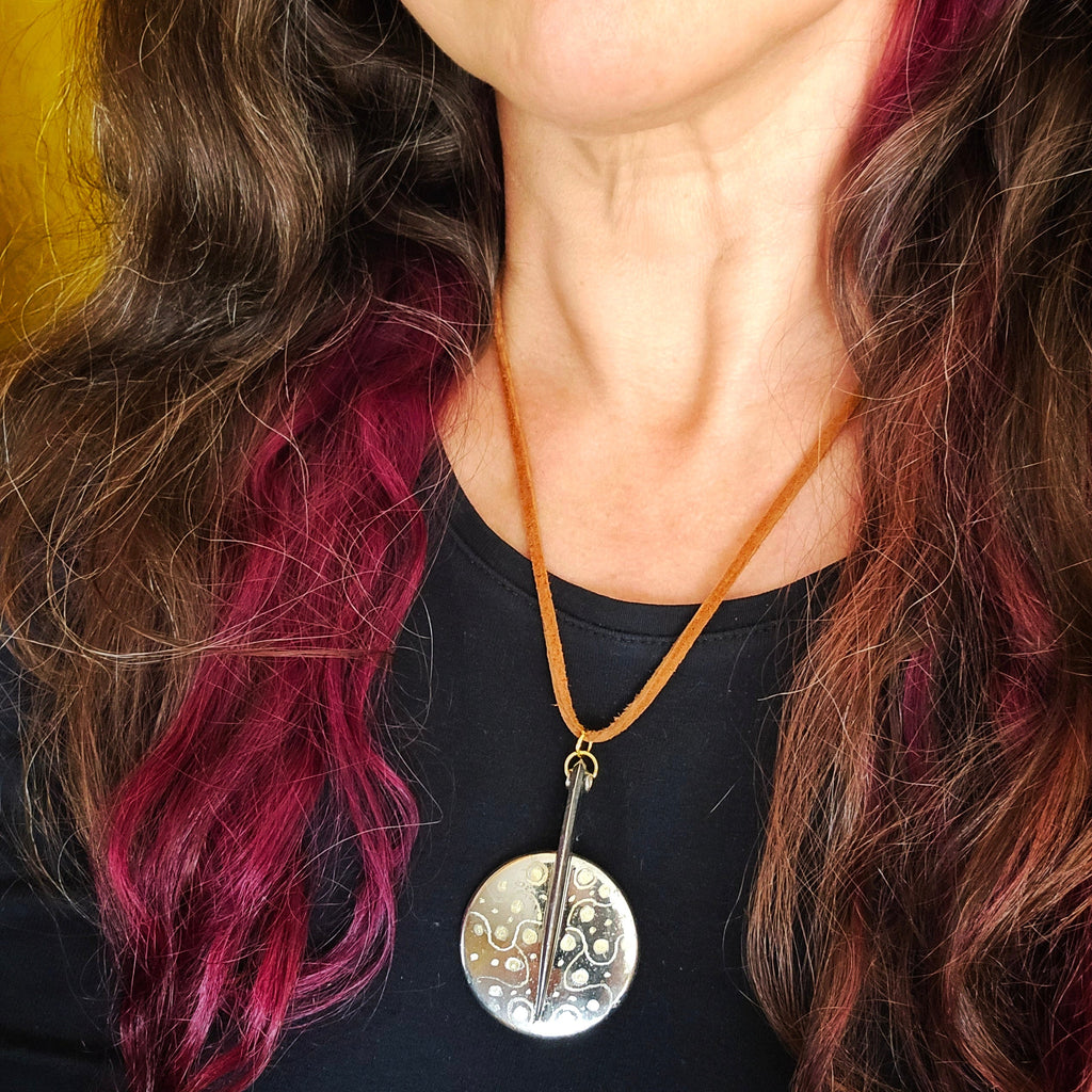 Woman wearing a necklace with an upcycled saxophone key pendant against a blurred background