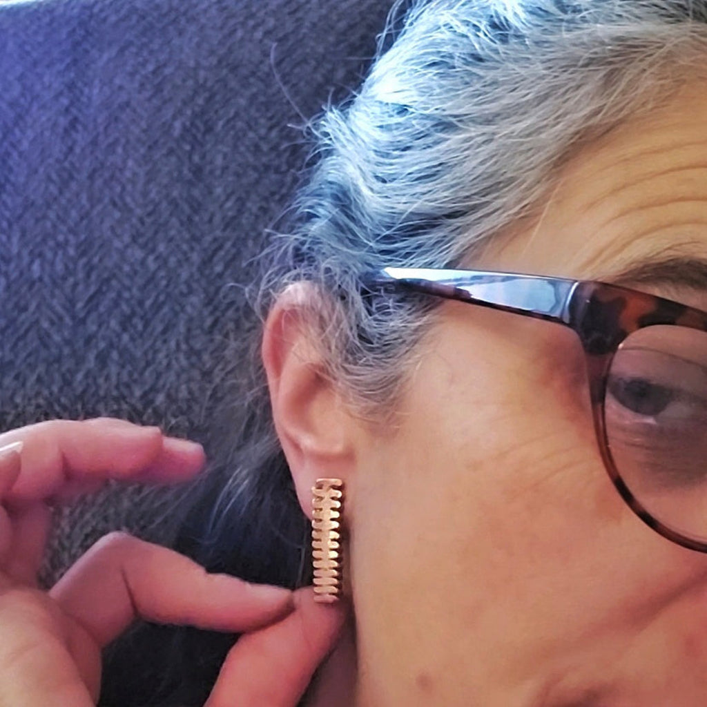 Woman wearing upcycled copper piano string earrings 