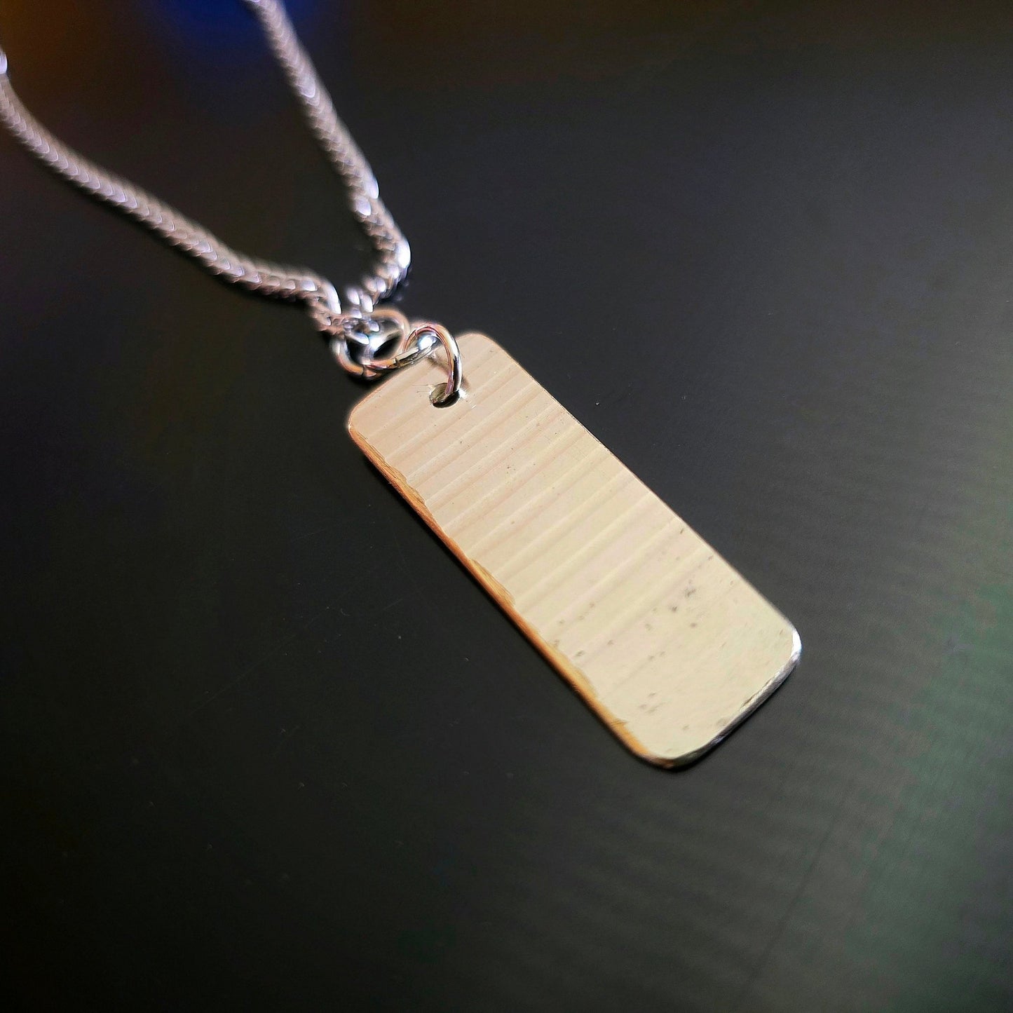 dog tag style upcycled cymbal piece necklace black background 