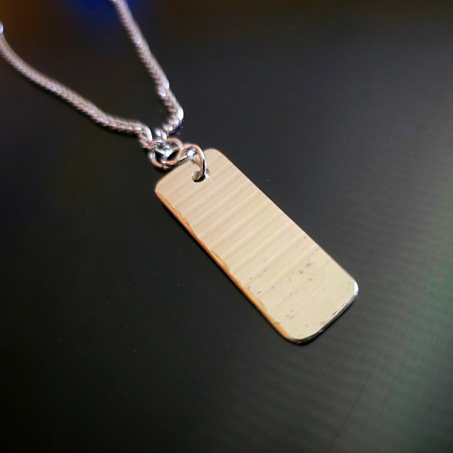 dog tag style upcycled cymbal piece necklace black background 