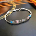 braided trans pride guitar string bracelet on black guitar