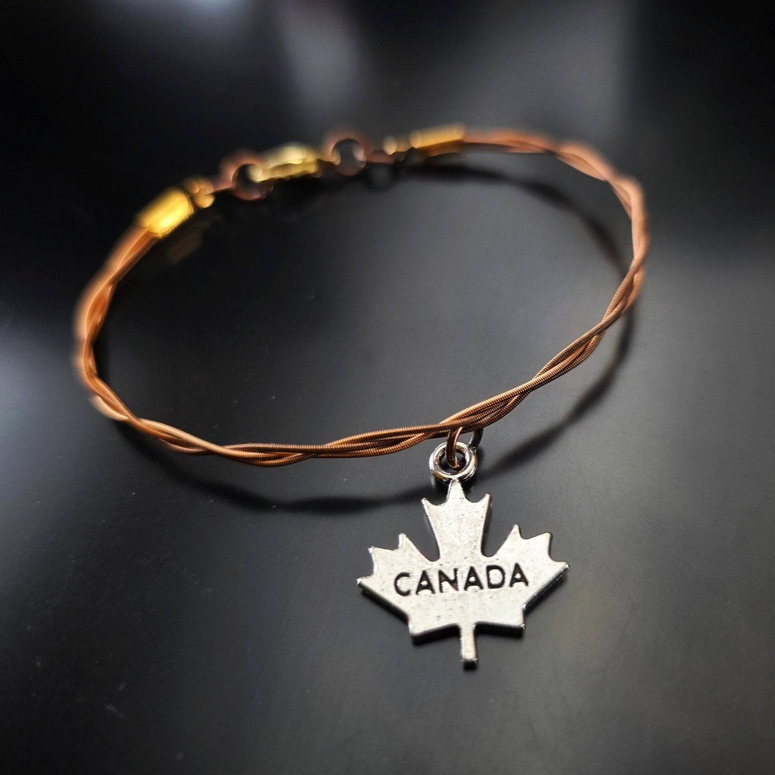 bronze coloured guitar string bracelet with canada maple leaf pendant