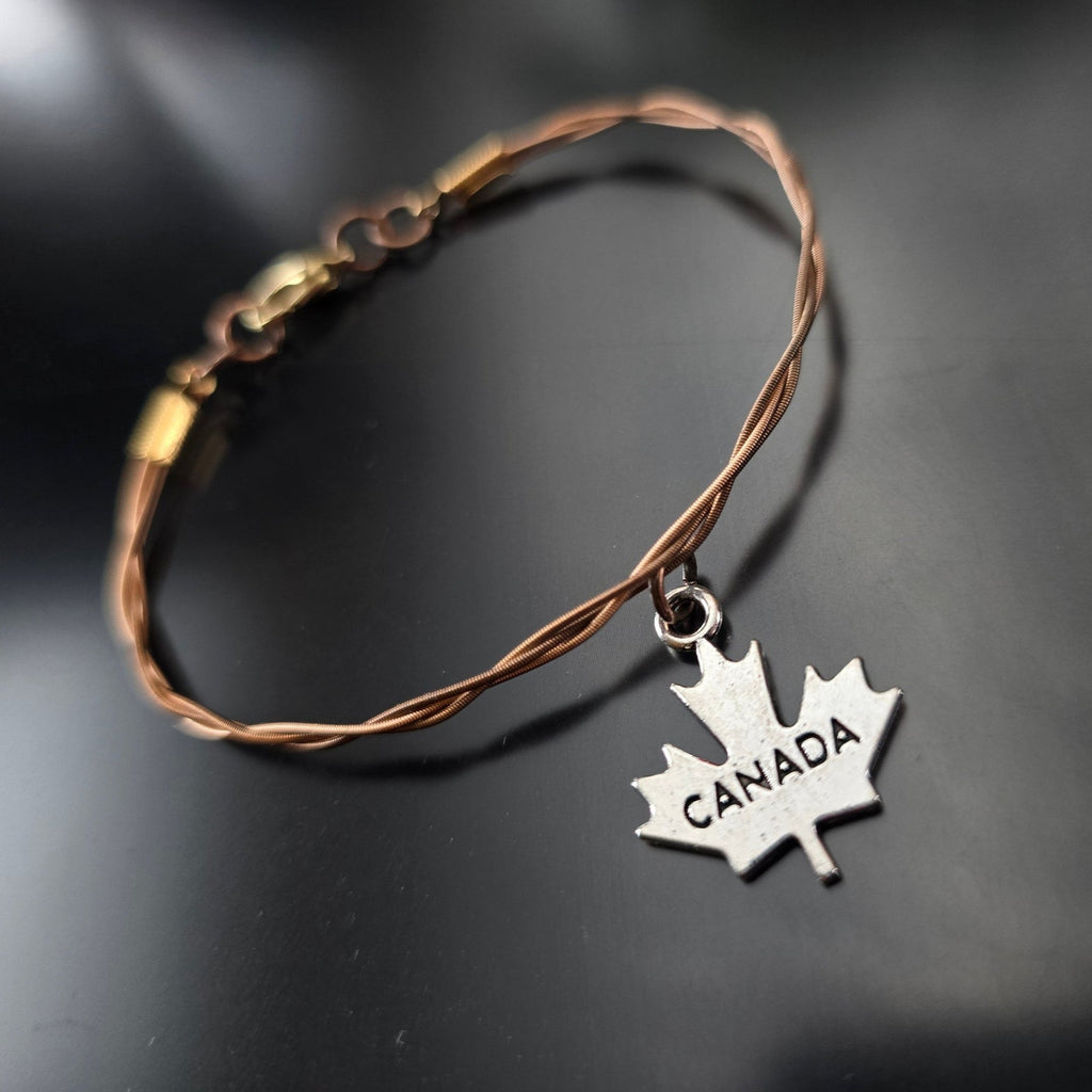 bronze coloured guitar string bracelet with silver coloured canada maple leaf pendant 