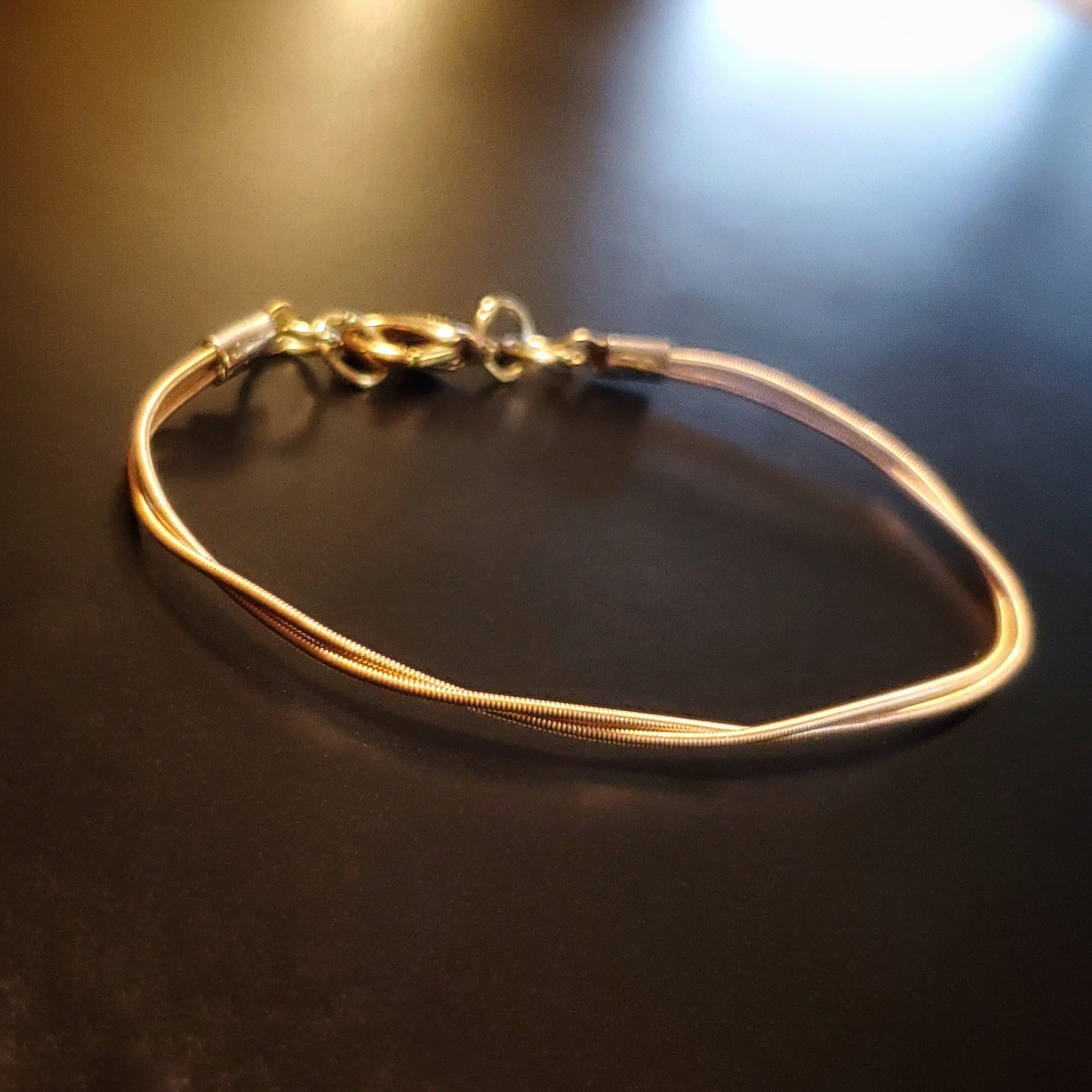 clasp style bracelet made from an upcycled mandolin string on dark background