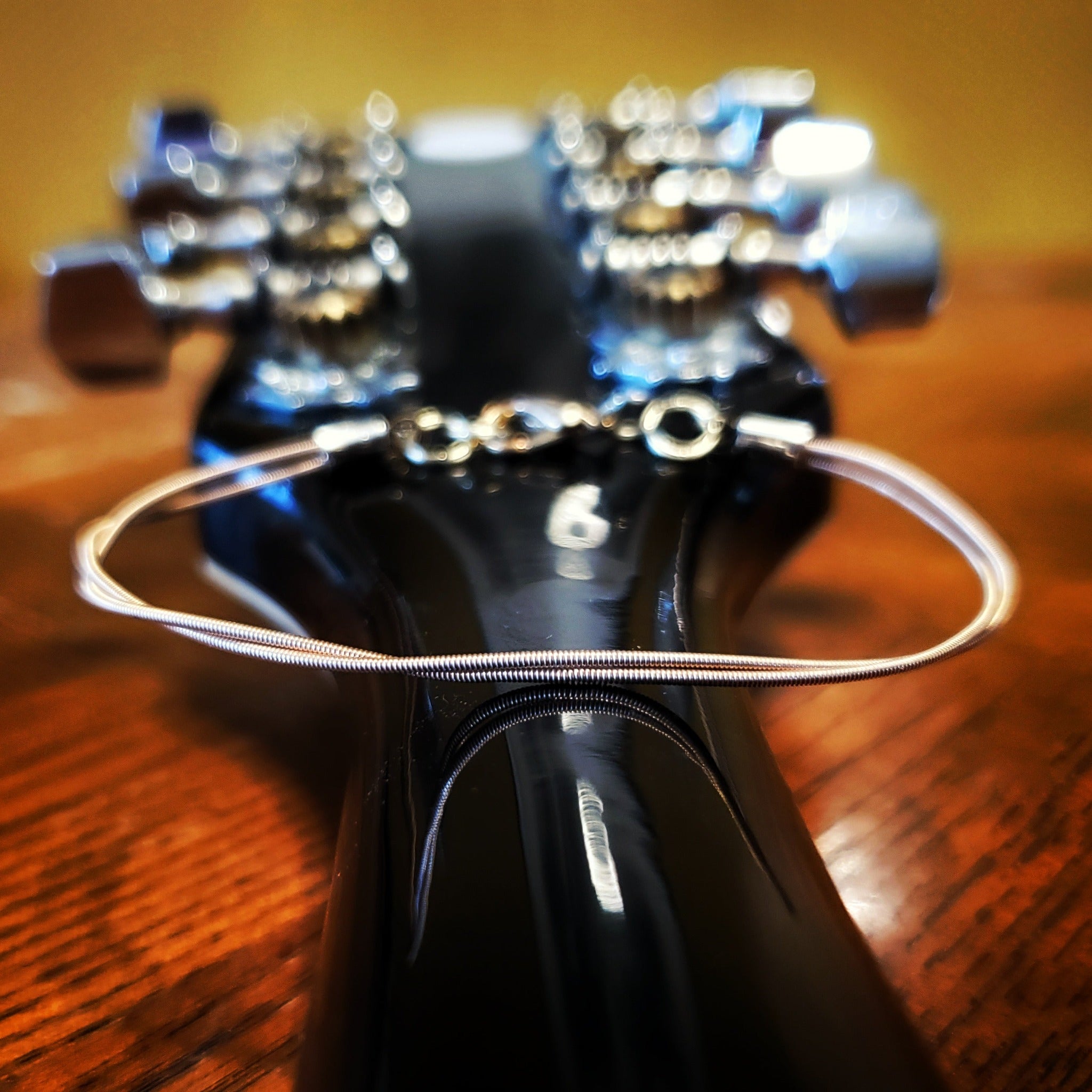 clasp style bracelet made from an upcycled mandolin string sitting on the back of the neck of a mandolin