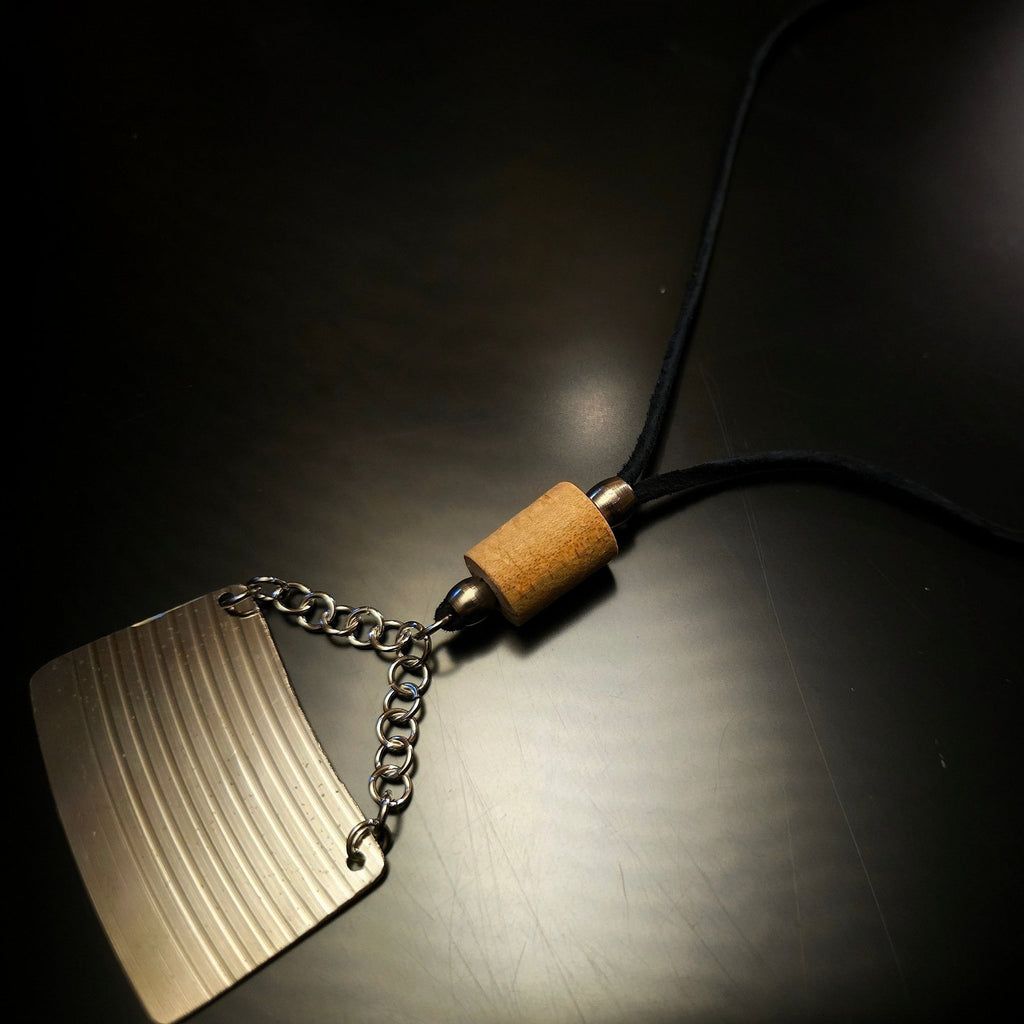 closeup of cymbal piece and drumstick black suede necklace black background