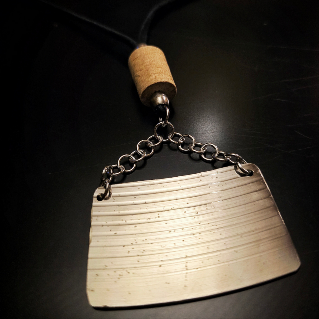 closup of upcycled drumstick and cymbal necklace on black background