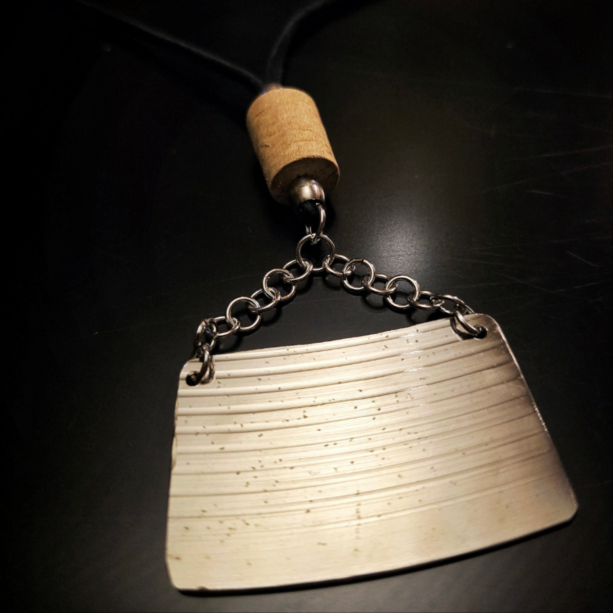 closup of upcycled drumstick and cymbal necklace on black background