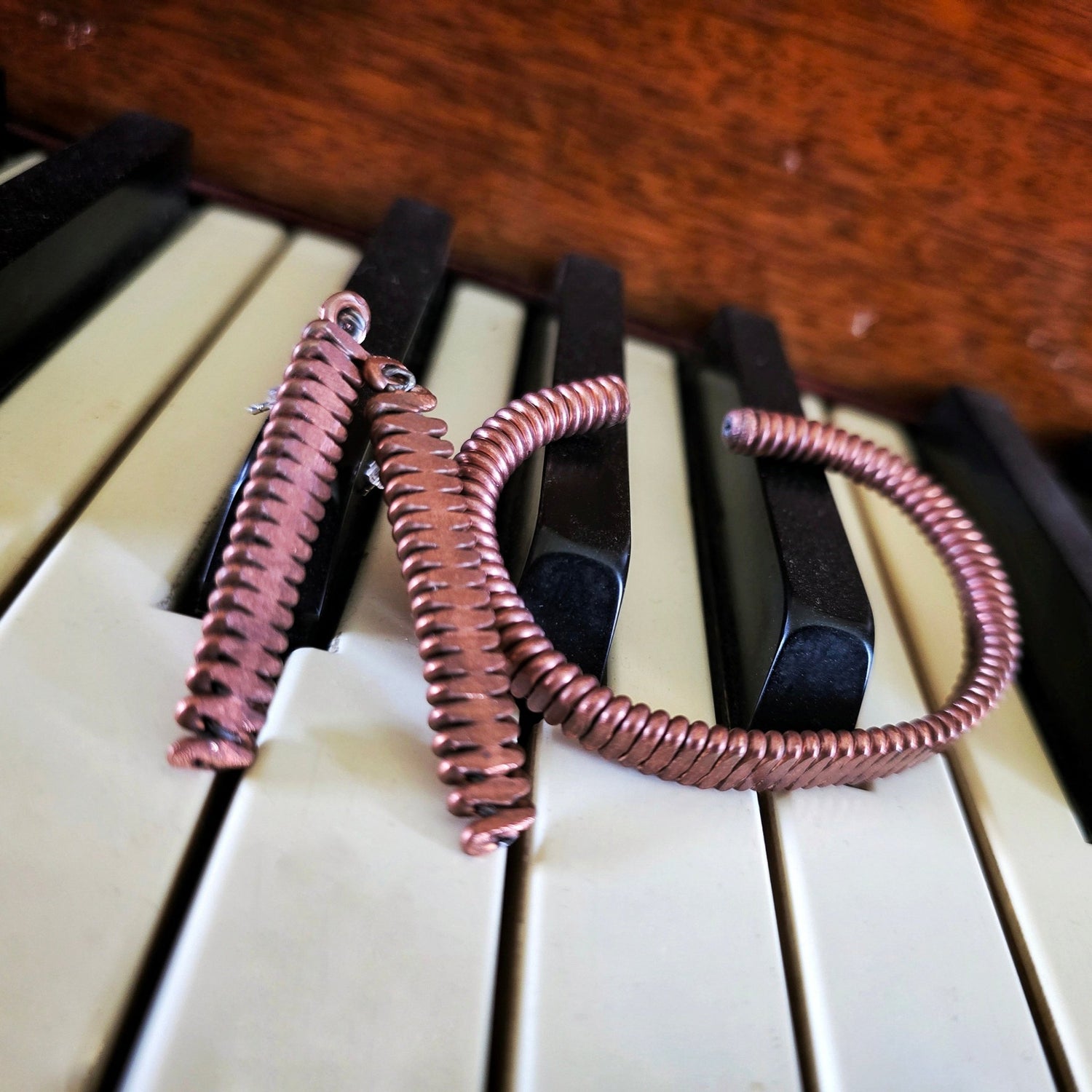 Upcycled Piano String Bracelets and Earrings Set on a piano 