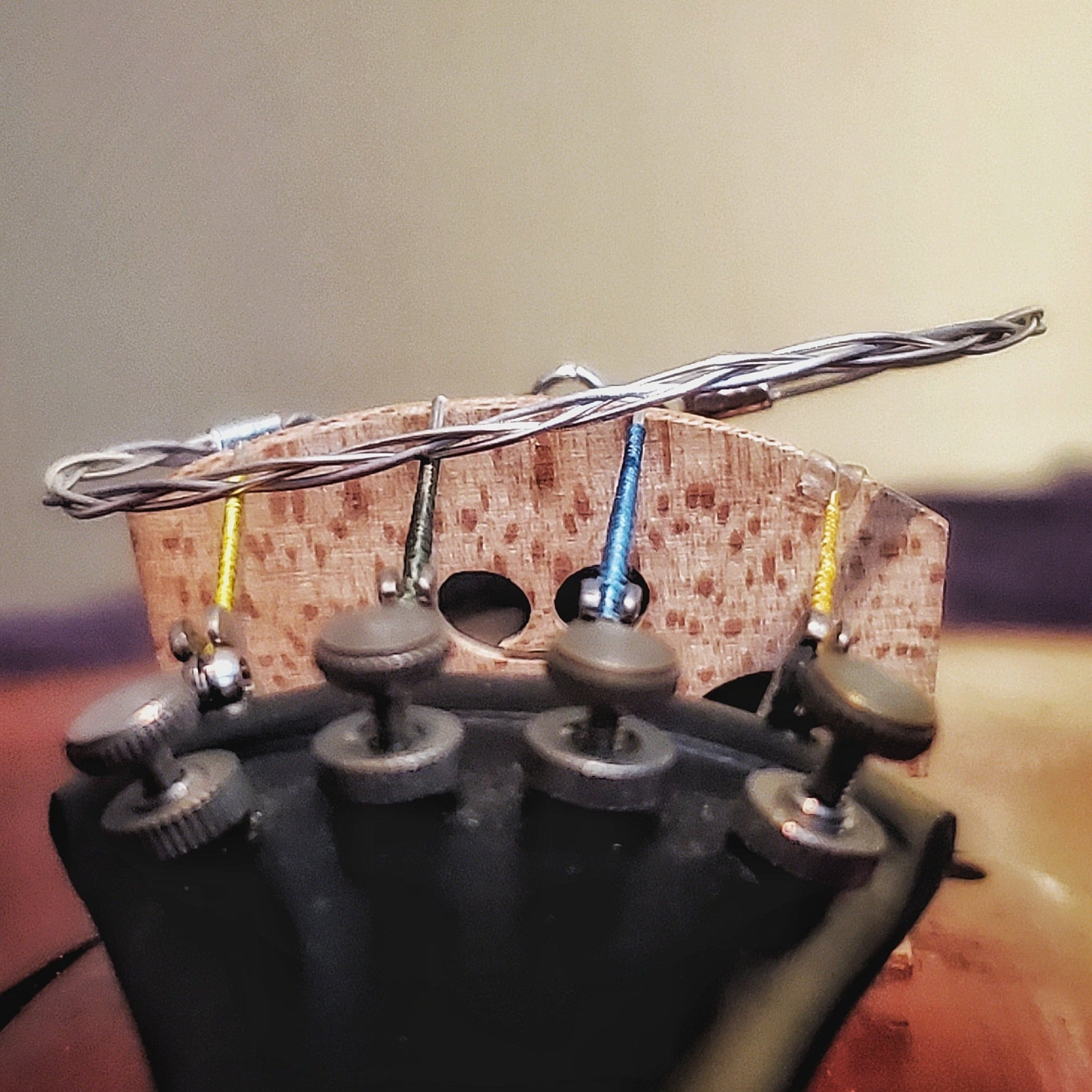 front view silver coloured violin string bracelet sitting on the bridge of a violin