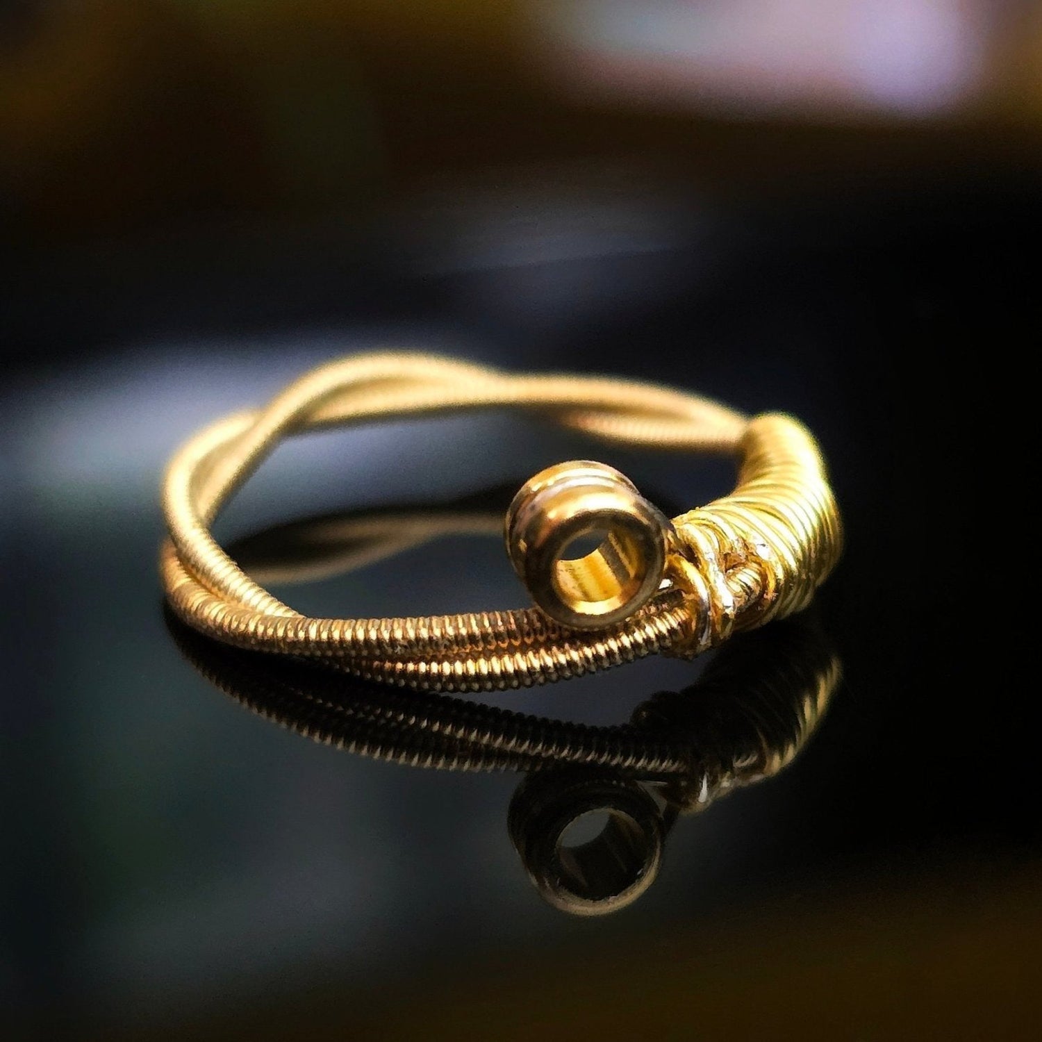 gold coloured upcycled guitar string ring black background