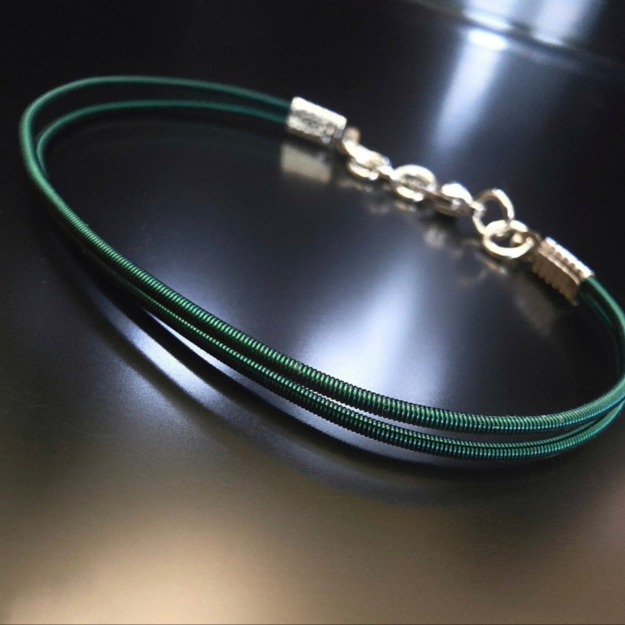 green harp string clasp style bracelet on black background