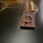 guitar string fidget ring sitting on the bridge of a black guitar