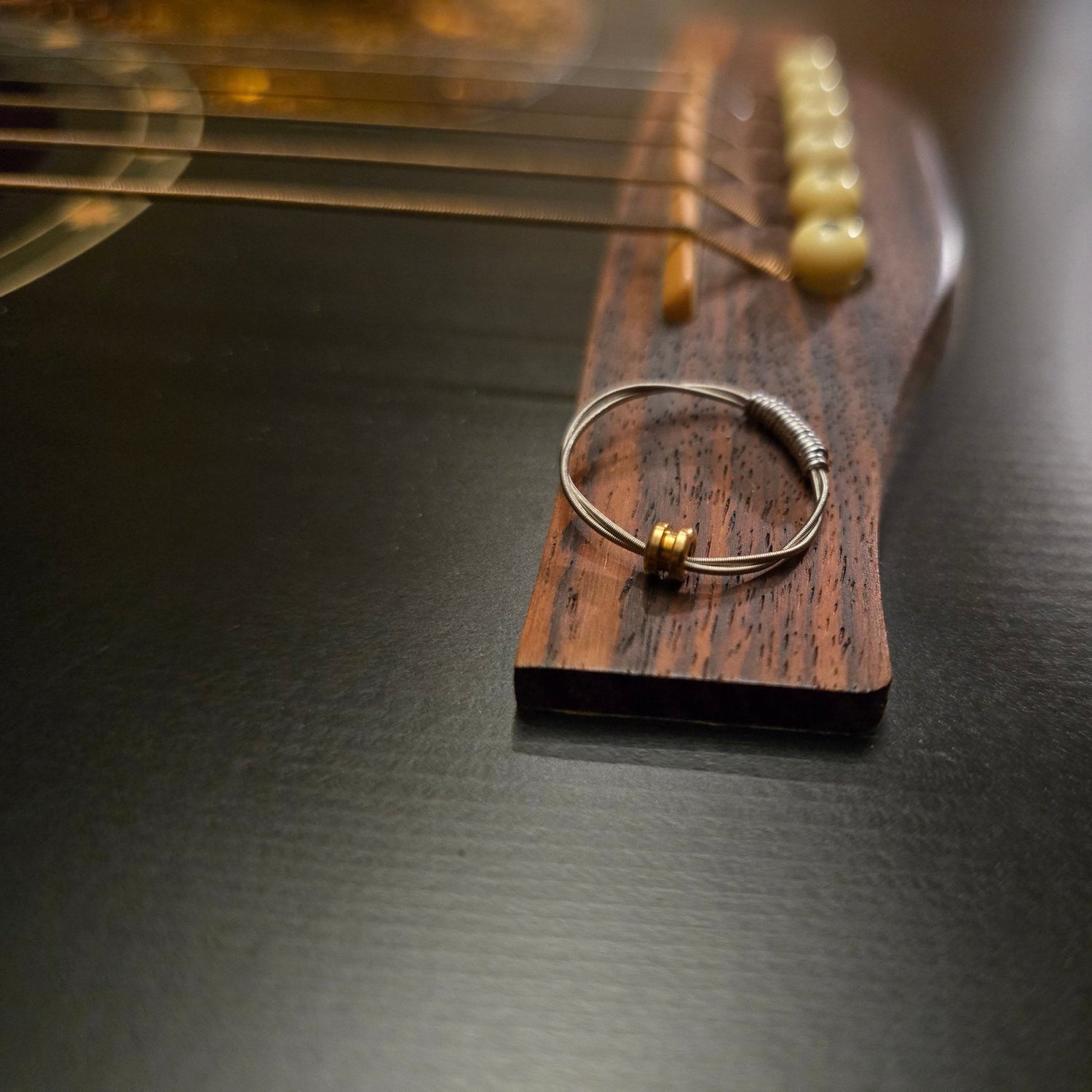 guitar string fidget ring sitting on the bridge of a black guitar