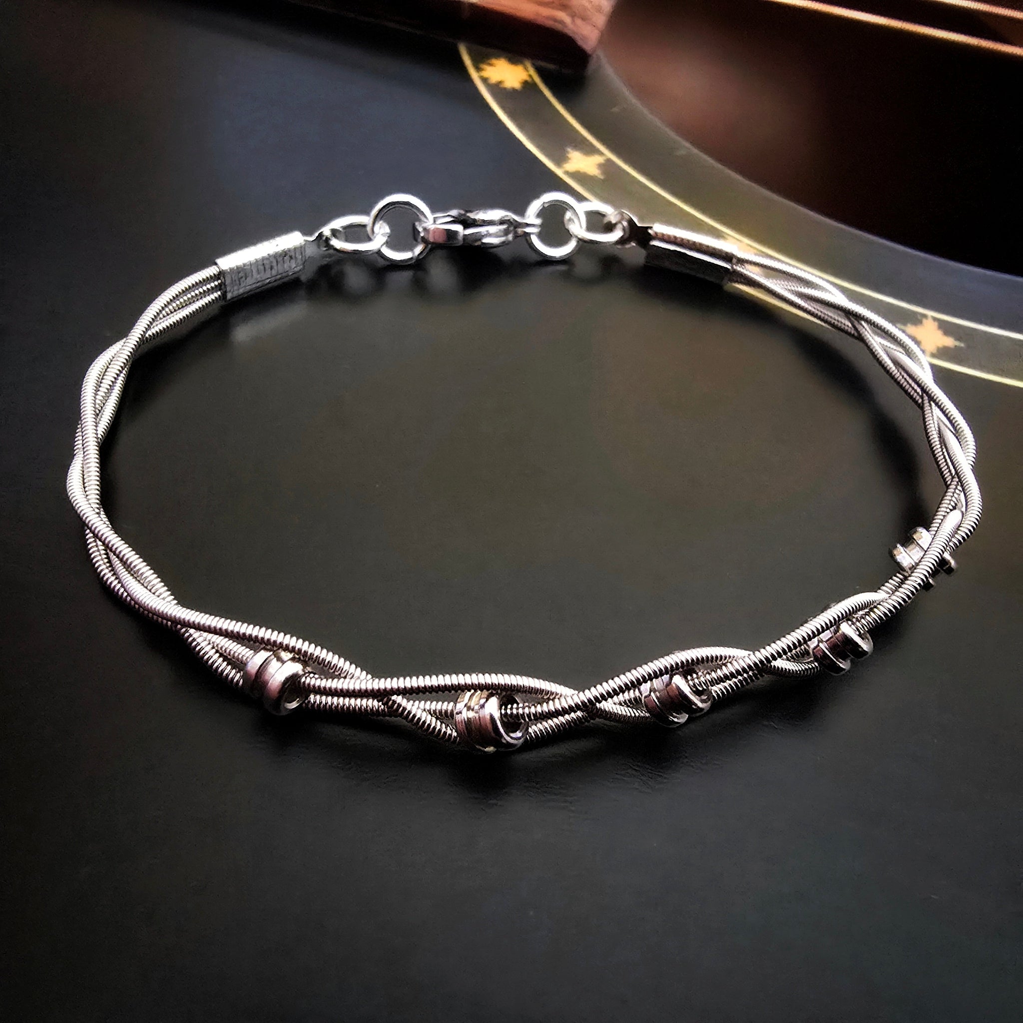 Silver guitar string bracelet on a dark guitar