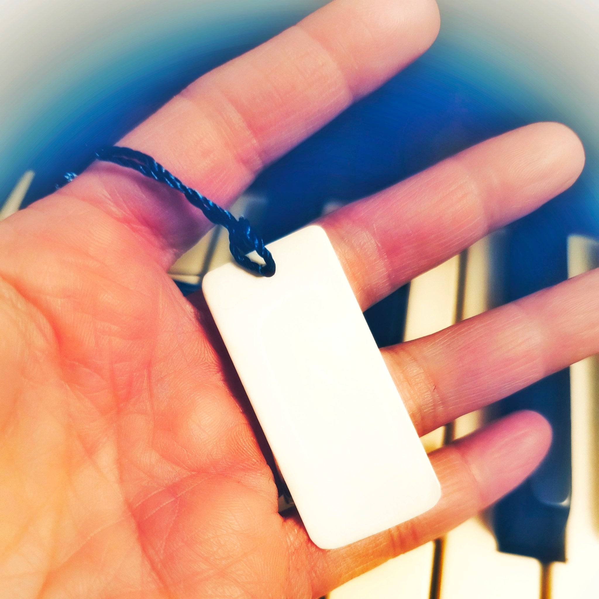 hand holding ivory piano key bookmark with piano in background