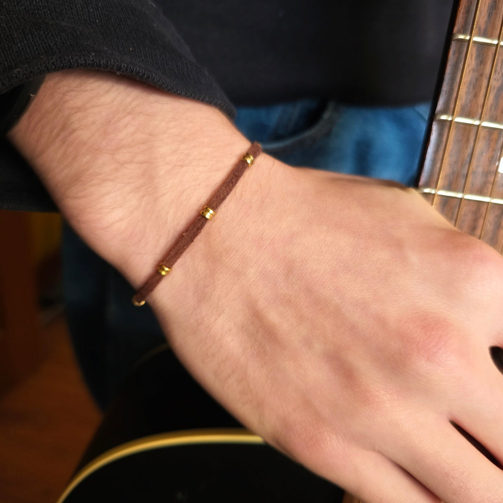 hand with suede ballend bracelet holding the neck of a guitar