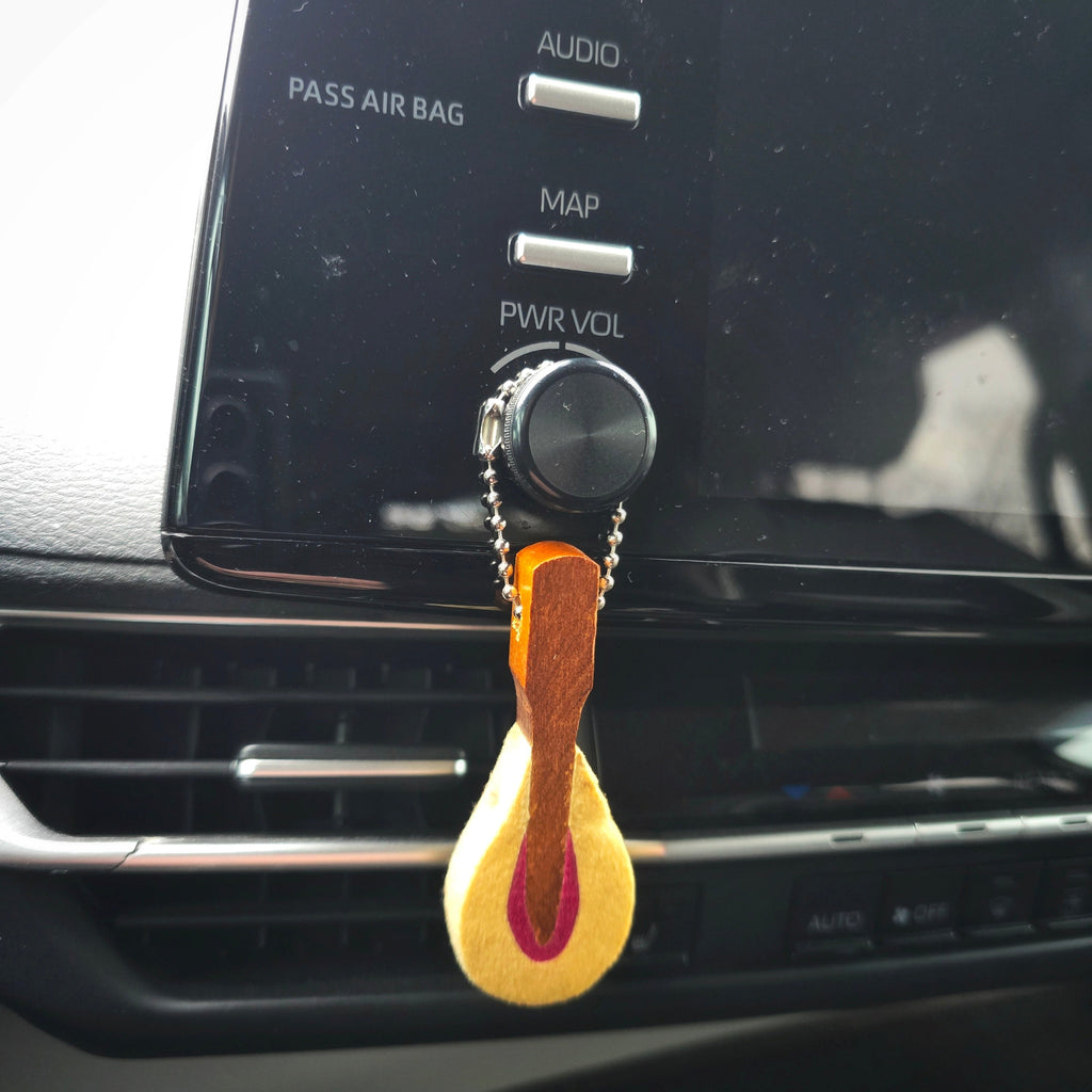 Car dashboard with a piano hammer diffuser hanging from the air vent.