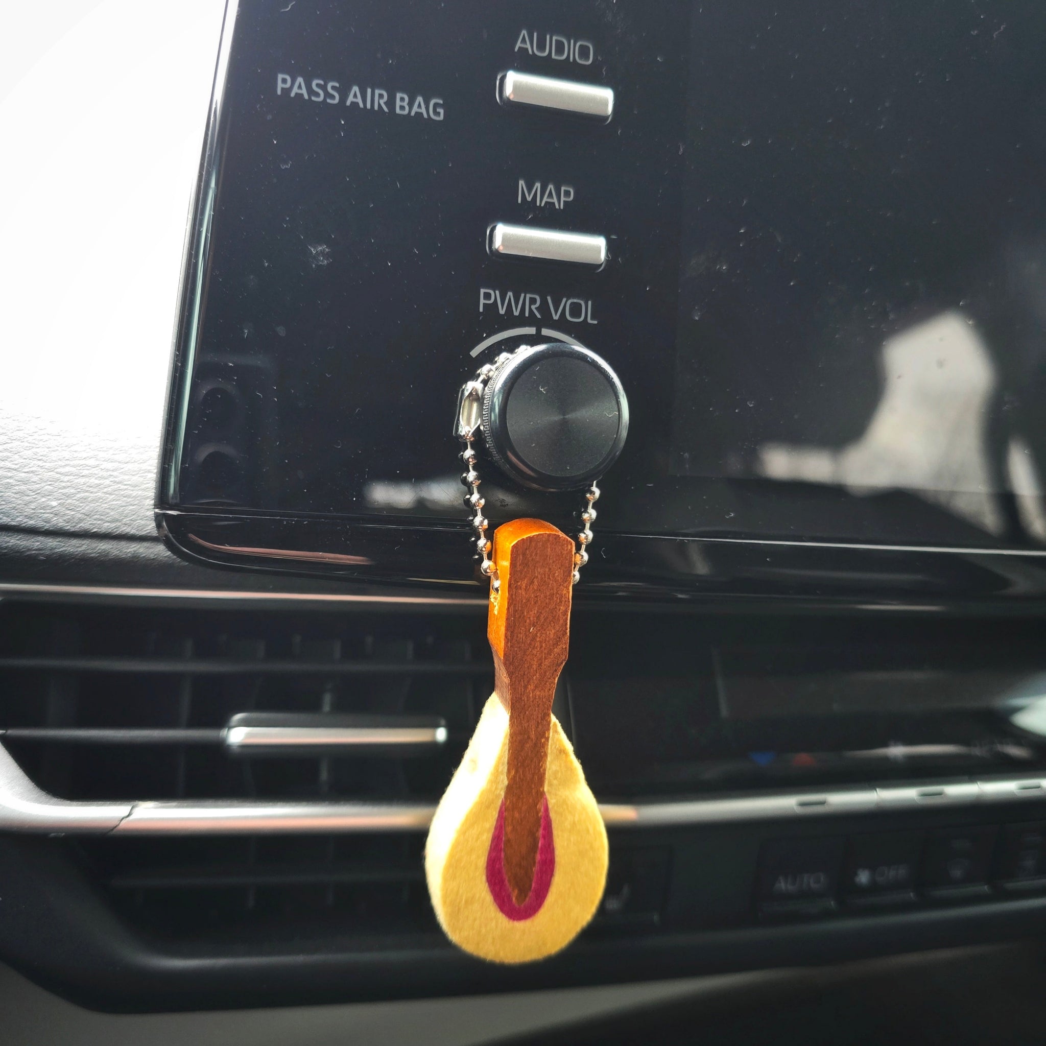 Car dashboard with a piano hammer diffuser hanging from the air vent.
