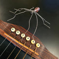 Close-up of a guitar's fretboard with guitar string spider on a dark background