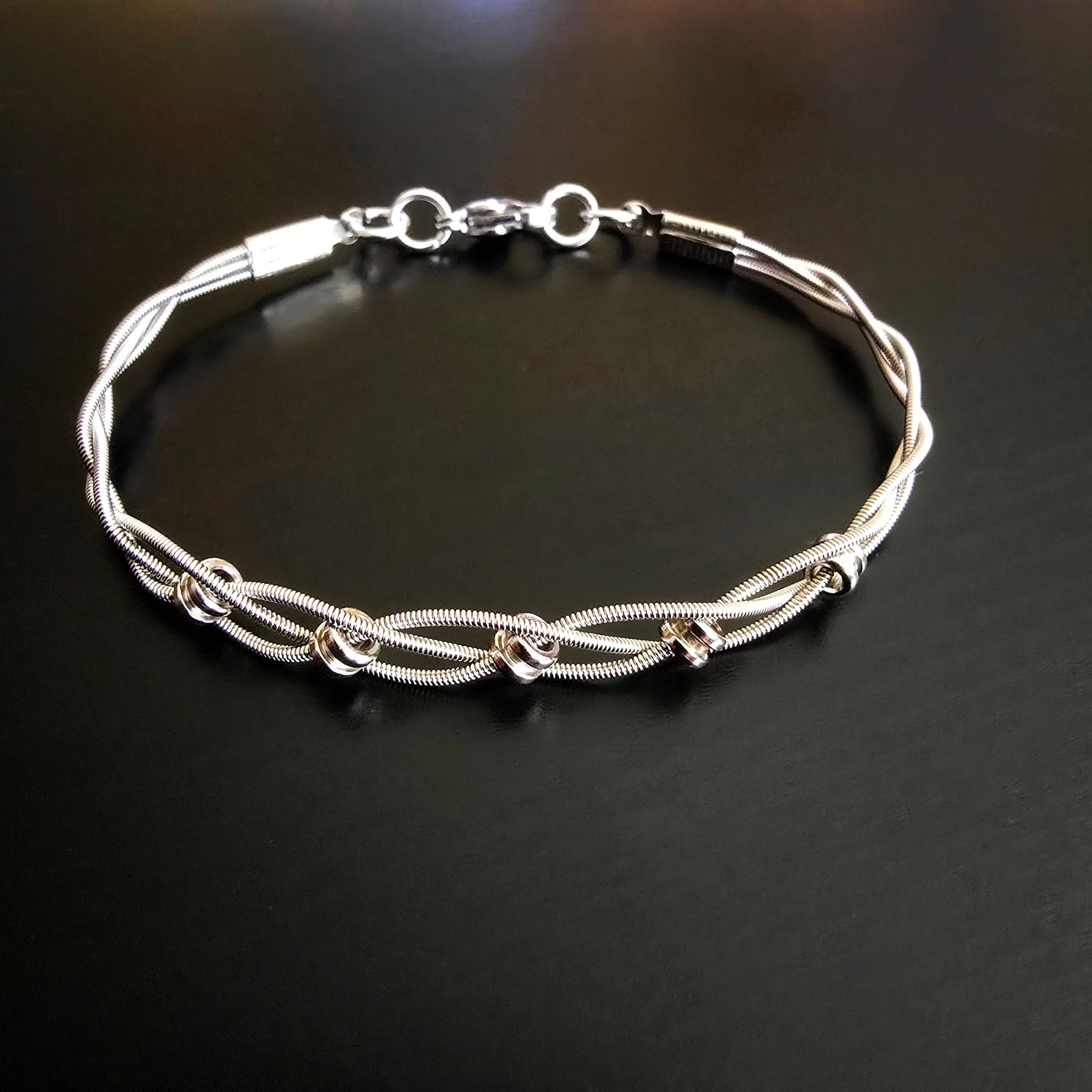 upcycled silver guitar string bracelet black background