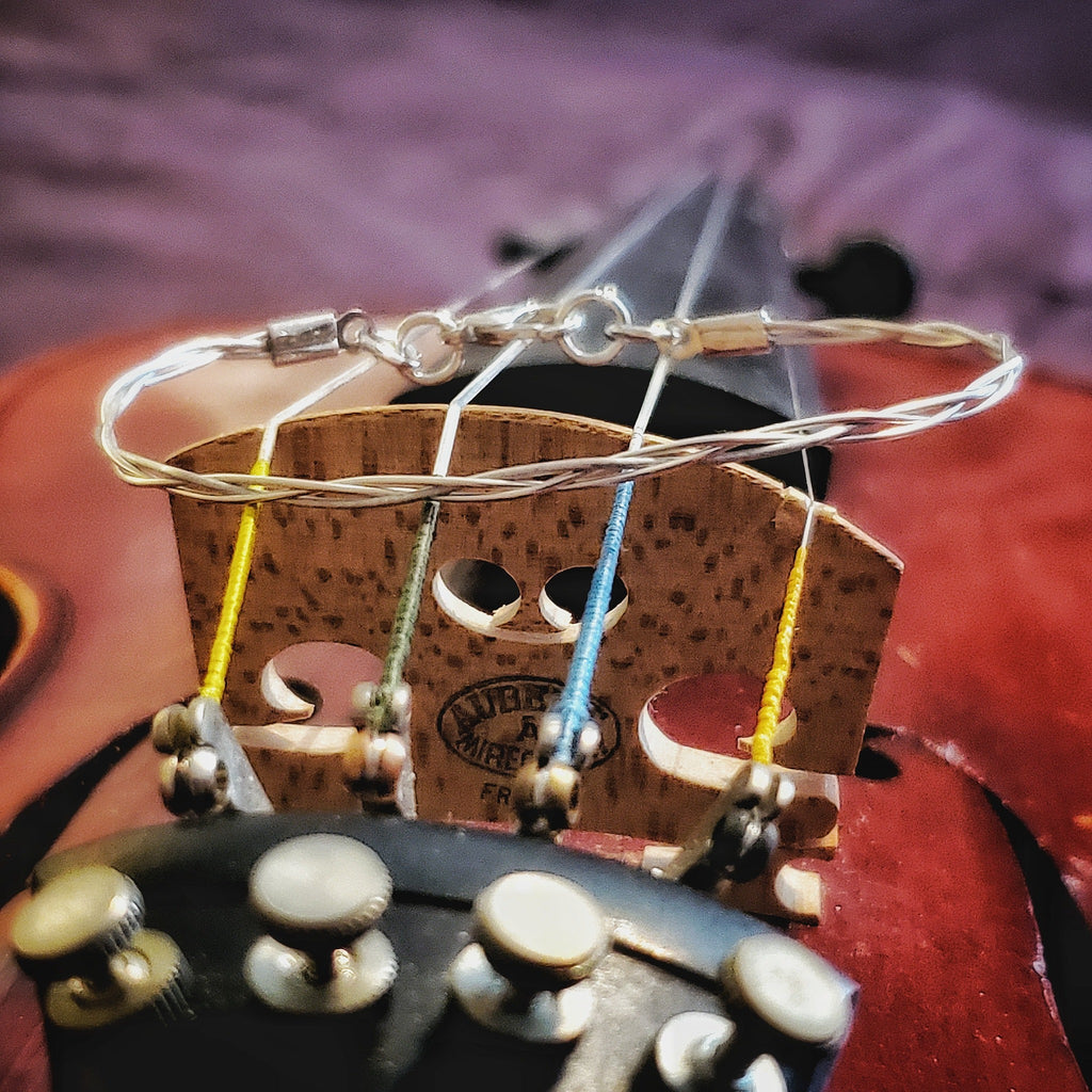 silver coloured violin string bracelet sitting on a violin bridge