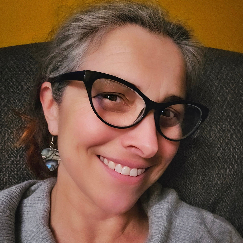 Smiling woman with glasses wearing guitar pick earrings 