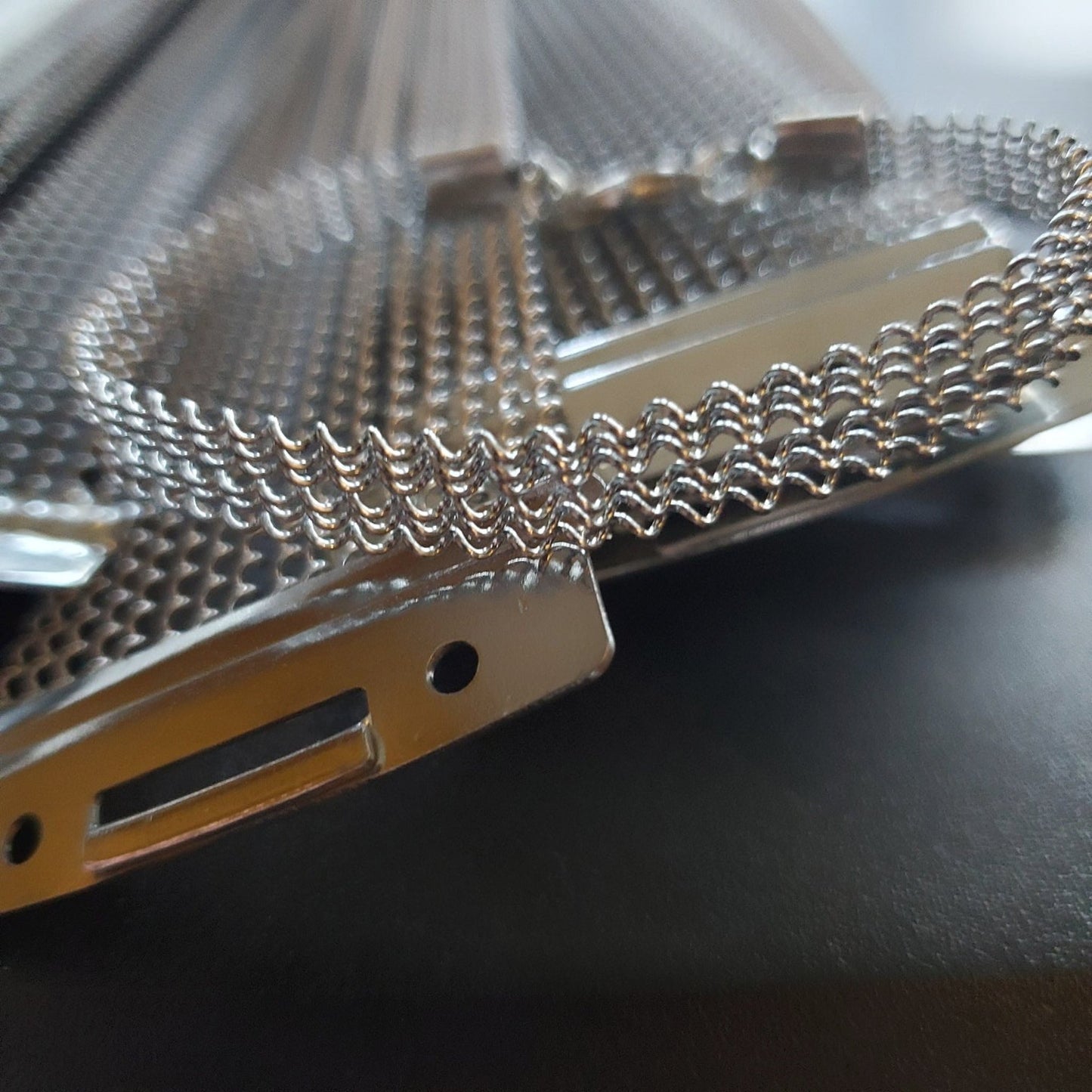 close-up of silver coloured bracelet made from upcycled snare drum strings sitting on a pile of snare drum strings