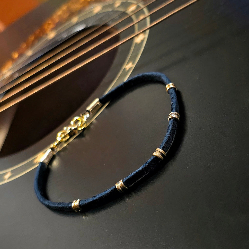 suede and guitar strings ballend bracelet on black guitar