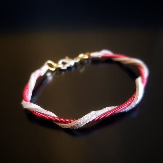 upcycled harp string and suede bracelet on a black background