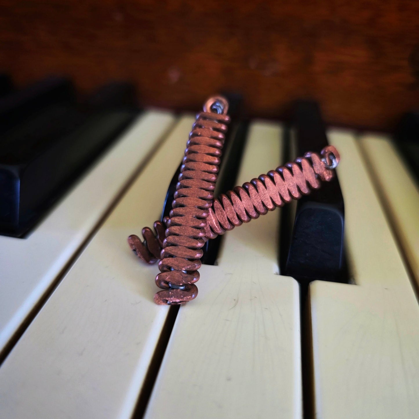 Upcycled Piano String Copper Earrings on a piano 